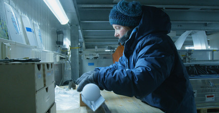 Eine Person in gekühltem Labor oder Werkstatt arbeitet in dicker Winterkleidung.