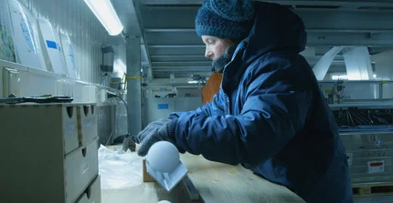 Eine Person in gekühltem Labor oder Werkstatt arbeitet in dicker Winterkleidung.