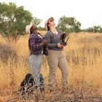 NamTip researchers looking up in the sky at a drone flying over a dry savanna rangeland