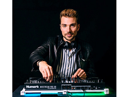 Ein Mann mit dunkler Jacke an einem DJ Pult