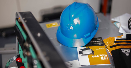 Close-up shot in the IT workroom. A blue hard hat with the lettering ‘University of Potsdam’ can be seen.