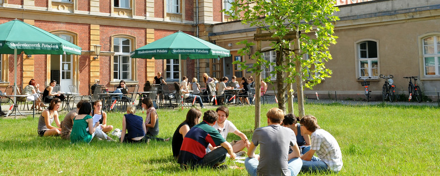 Innenhof Haus 8 am Neuen Palais, Studenten sitzen auf der Wiese und den Bänken vor der Cafeteria