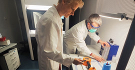 Two people preparing the sample holder for cryo-electron microscopy.
