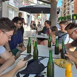 Die Studierenden sitzen an einem Tisch in einem Straßencafé und genießen kühle Getränke.
