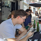 Die Studierenden sitzen an einem Tisch in einem Straßencafé und genießen kühle Getränke.