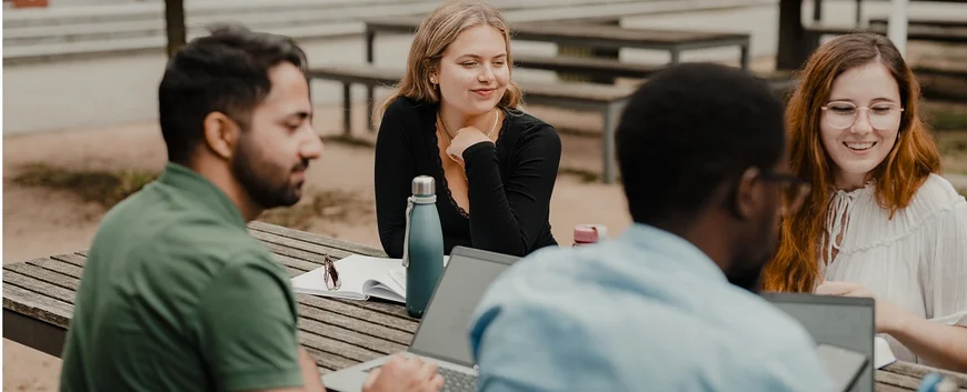 Profs sitting outside on campus with students