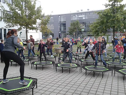 Kinder folgen dem Sportprogramm des Hochschulsports auf Trampolinen.