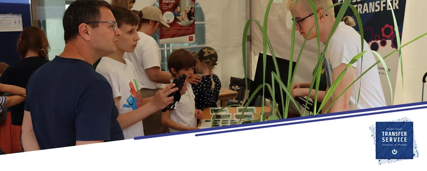 Vater und Sohn stehen an einem Stand und schauen sich diverse kleine Pflanzen an