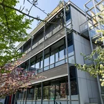 Steel and glass front of a research building, two trees in front of it