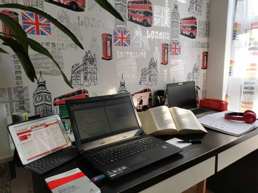 Ein Schreibtisch mit zwei Laptops, zwei stühlen, mehreren Büchern