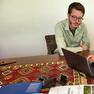 Drei Männer sitzen an einem Tisch und schauen in einen Laptop
