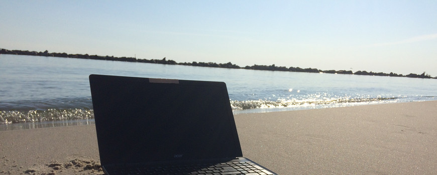 Handtuch am Strand mit Laptop und Büchern drauf