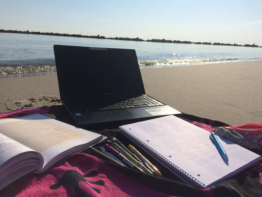 Handtuch am Strand mit Laptop und Büchern drauf
