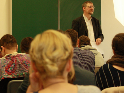 Eine Seminarsituation im Rahmen der Ringvorlesung "Was sind Jüdische Studien?" im Winter 2014. Hinterköpfe von Studierenden im Vordergrund. Prof. Dr. Thomas Brechenmacher im Hintergrund vor einer Tafel.