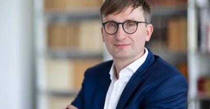 Portrait von Professor Dr. Sönke Neitzel vor einem Bücheregal