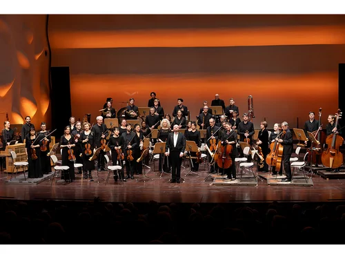 Großes Orchester mit Dirigent im Vordergrund
