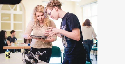 Zwei Frauen arbeiten mit einem Laptop und einem Roberta Roboter