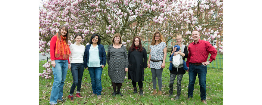 die Mitarbeiter des Lehrstuhls stehen unter der blühenden Magnolie hinter Haus 8 am Campus Neues Palais