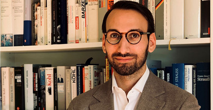 Portrait von Dr. Bastian Matteo Scianna vor einem Bücherregal.