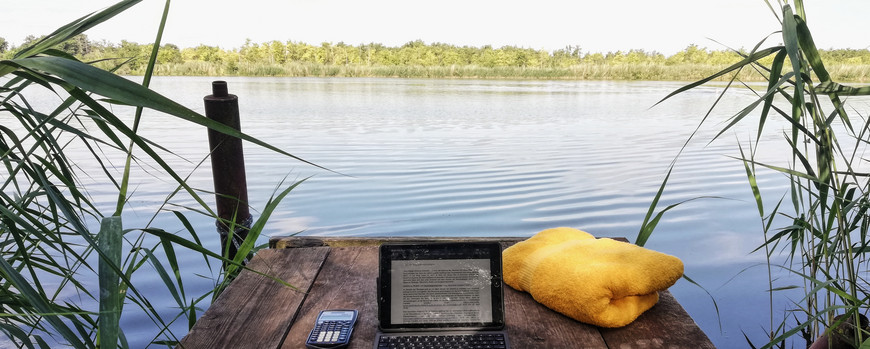 Laptop mit Handtuch auf Steg am See