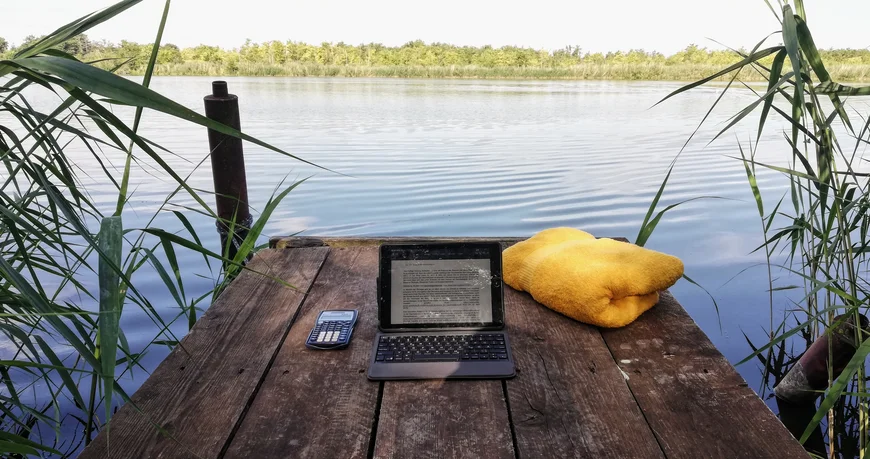 Laptop mit Handtuch auf Steg am See
