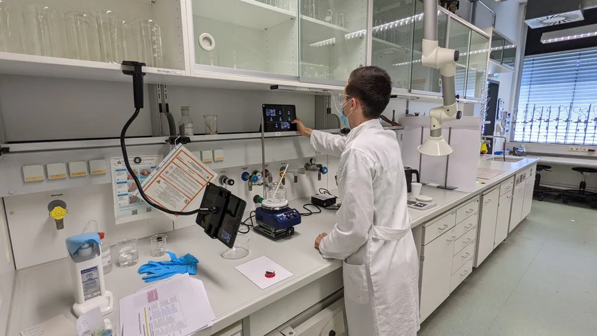 Student mit Schüler*innen bei der digitalen Laborarbeit