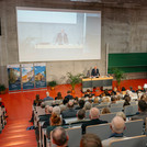Ein Hörsaal mit Personen im Saal und einer Person auf dem Podium
