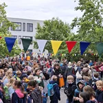 Viele Kinder auf einem Platz zwischen Bäumen und Gebäuden
