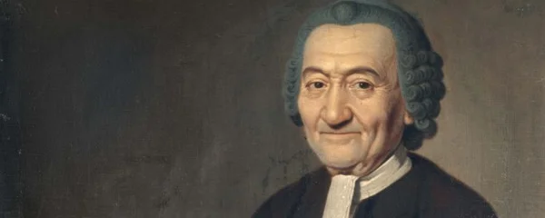 Raphael Levi mit Perrücke vor grauer Wand