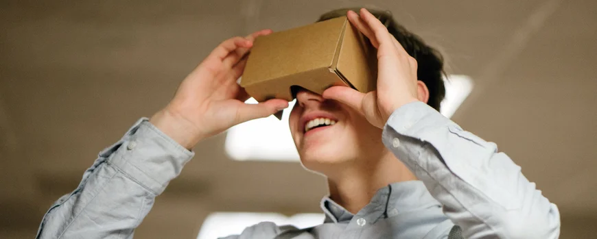 Ein Schüler blickt in eine Papphalterung für Virtual-Reality-Anwendungen auf dem Smartphone
