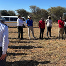 Menschen stehen auf einer Rasenfläche in Namibia, eine von ihnen erzählt