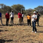Menschen stehen auf einer Rasenfläche in Namibia, eine von ihnen erzählt