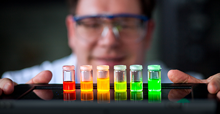 Farbige Reagenzgläser stehen in Reihe in einem Labor.