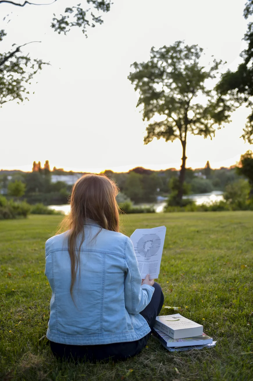 Mensch mit Rückenzur Kamera mit Büchern mit Blick auf die Havel. Sonnenuntergang