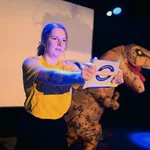 Eine Person und eine T-Rex Figur auf einer Bühne