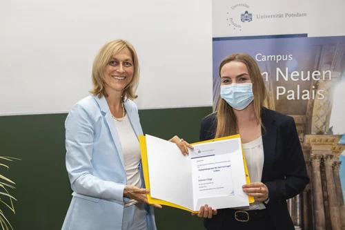 Die Studiendekanin überreicht der Preisträgerin Juliane Clegg die Urkunde für den Lehrpreis 2022.