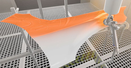 Eine virtuelle Lernumgebung, in der ein Fahrzeugteil mit einer Lackierpistole mit orangener Farbe besprüht wird.