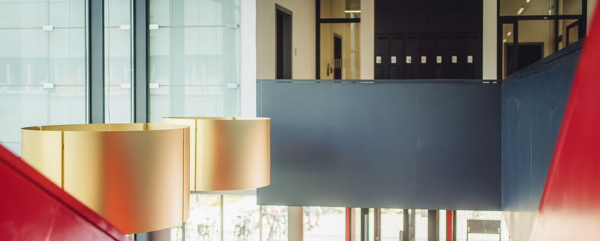 Eine Studentin und ein Student stehen in Haus 28 in Golm auf einer Treppe und unterhalten sich.