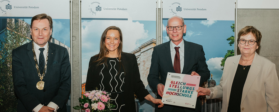 Vier Personen posieren für ein Foto. - 