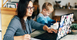 Mutter im Homeoffice am Laptop mit Kind. Das Foto ist von AdobeStock/Ilona.