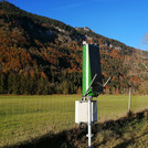 Field site Graswang: Two CRNS sensors with solar panels installed next to a single tree at a green pasture valley bottom. In the background are mountains with mixed autumn forest | Photo: Cosmic Sense Consortium