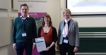 The awardee and two more people standing together at the award ceremony