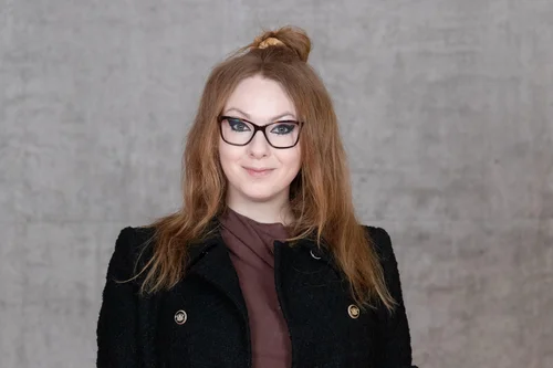 Frau mit rotblonden Haaren und Brille.