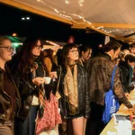Mehrere Personen vor einem erleuchteten Marktstand