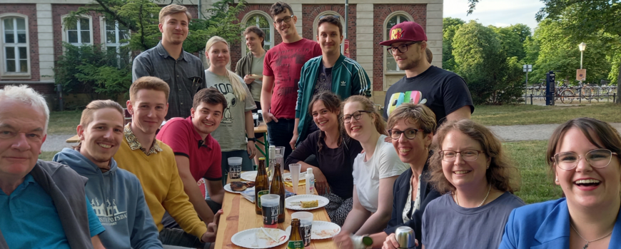 Studierende und Lehrende der Klassischen Philologie sitzen gemeinsam beim Essen vor Haus 12.