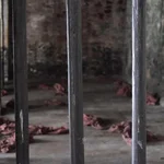 Raum hinter Gittern mit Kleidung der Gefangenen