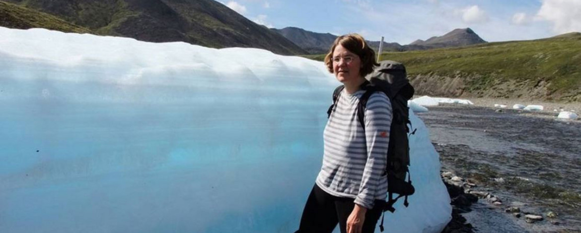 Prof. Ulrike Herzschuh steht im Gelände vor einem Eisblock - 