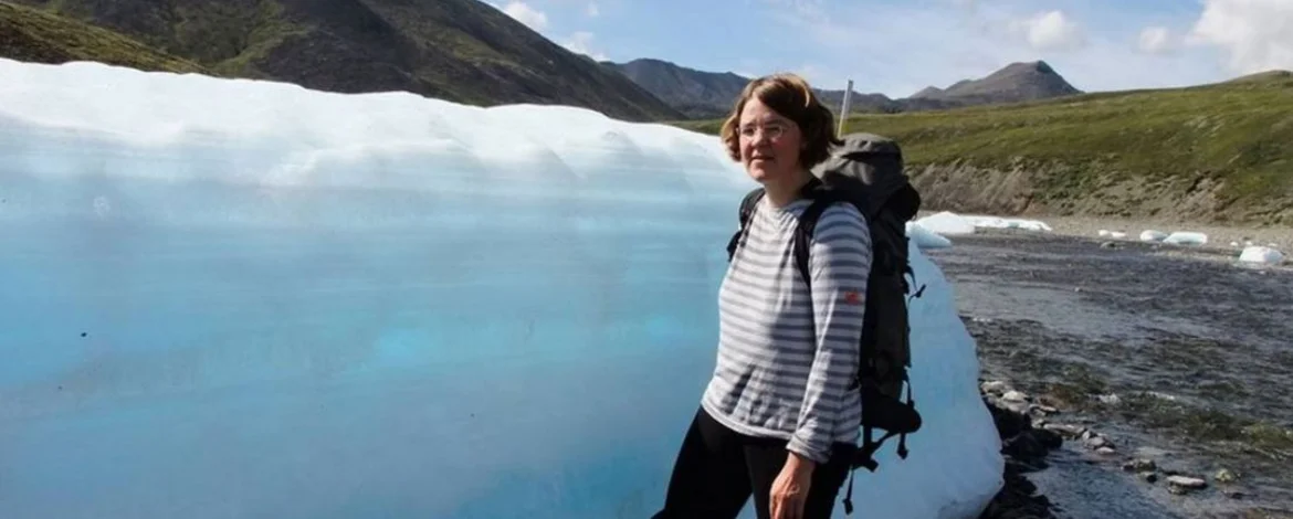 Prof. Ulrike Herzschuh steht im Gelände vor einem Eisblock - 