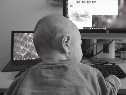 Kleinkind sitzt am Schreibtisch vorm Computer
