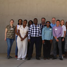 research group standing behind a wall